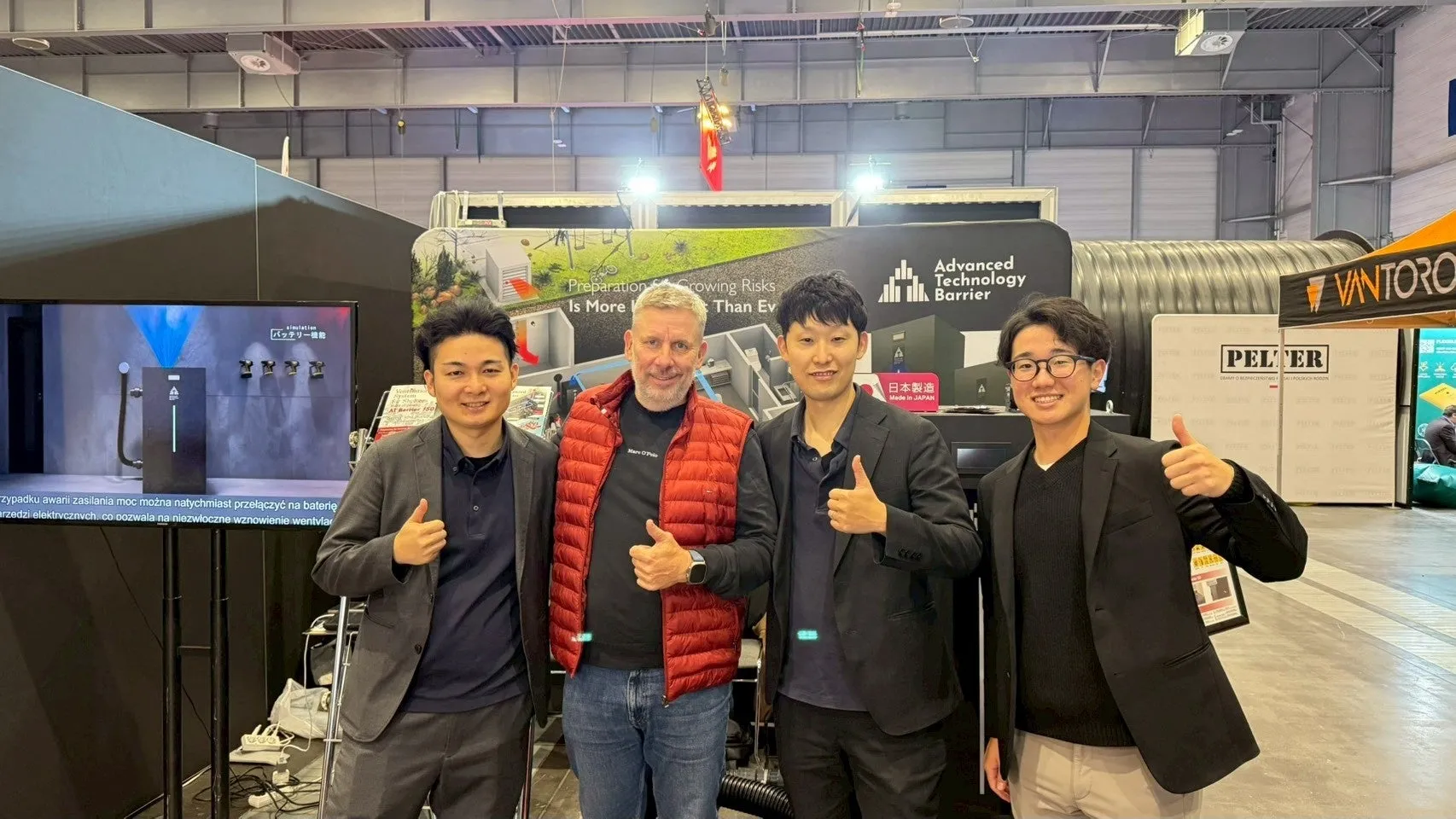 展示会でサムズアップをする4人の男性