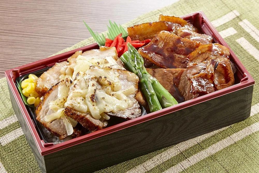 弁当箱に入った豚肉料理のアップ。チーズが乗った豚肉と、ソースで味付けされた豚肉が美味しそう。