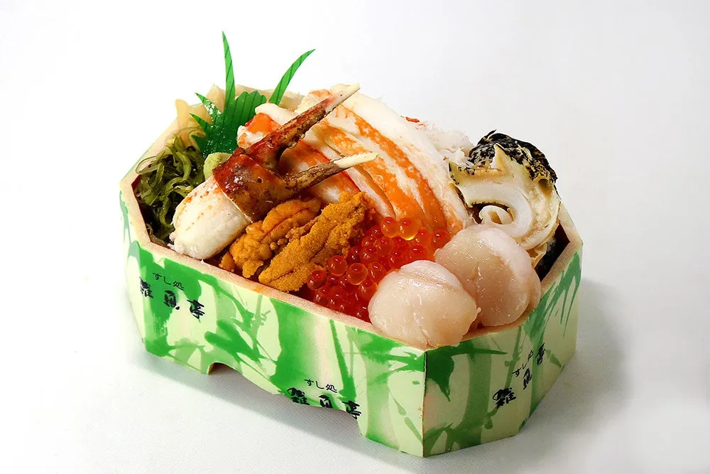 様々なお寿司が詰められた豪華な弁当の画像です。カニ、ウニ、イクラ、ホタテなど、新鮮な魚介類が美しく盛り付けられています。弁当箱は緑色の竹模様で、上品な印象を与えます。