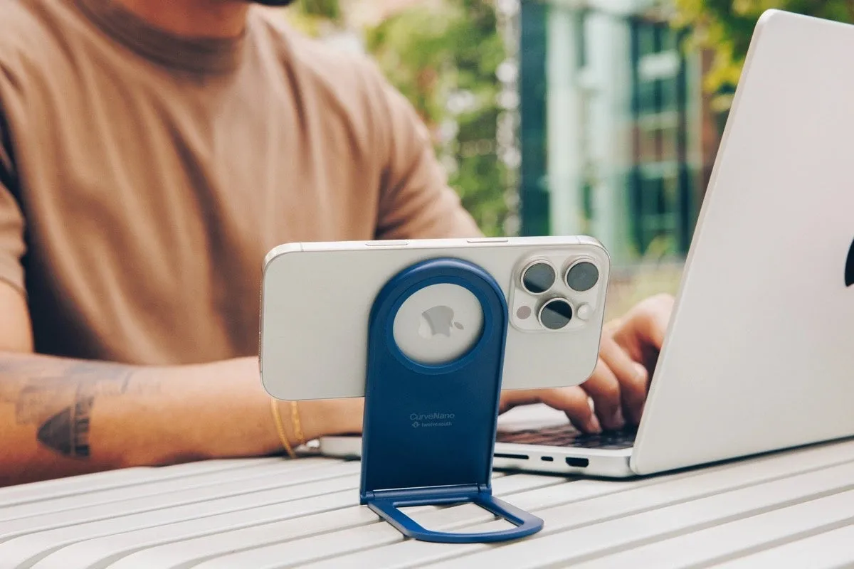 iPhoneがスタンドに立てかけられており、MacBook Proを使って作業している様子