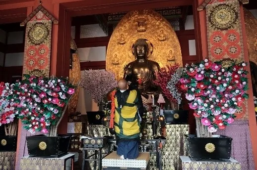 仏像の前で祈りを捧げる僧侶の画像です。