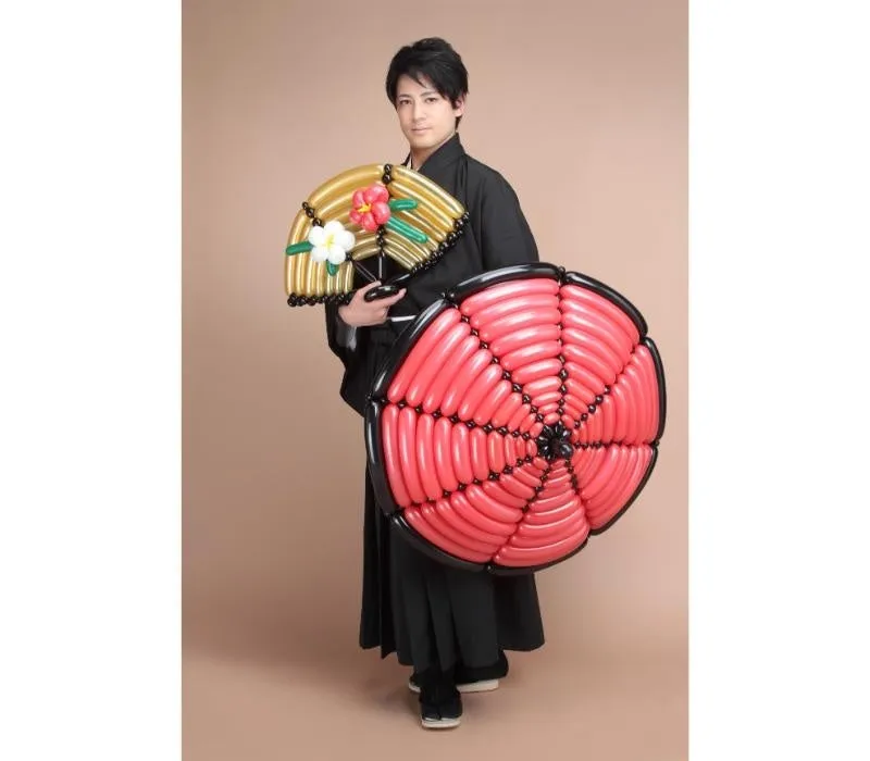 風船の扇子と赤い飾りを持つ男性