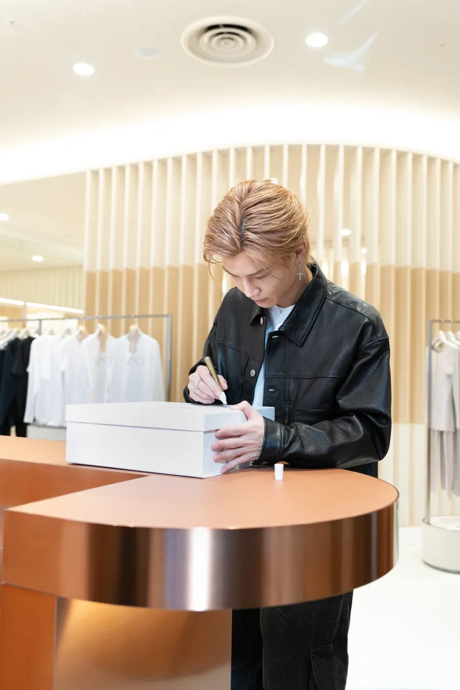 男性が白い箱にサインをしている様子を捉えた写真です。