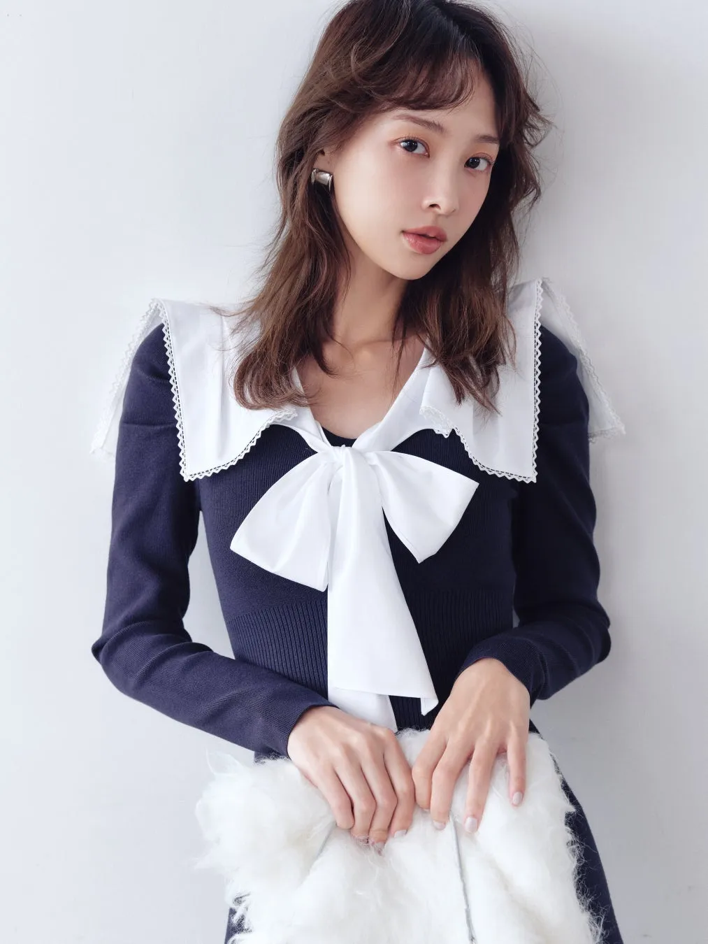 白い大きなリボンと白い襟のついた紺色のトップスを着た女性のポートレート。