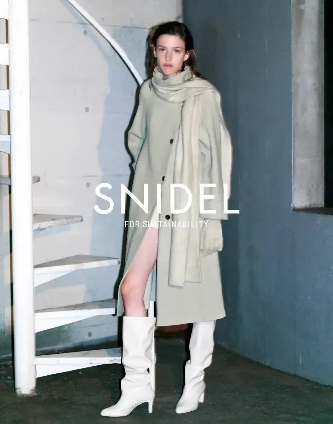 SNIDEL FOR SUSTAINABILITYのロゴと屋外に立つ女性のファッション広告