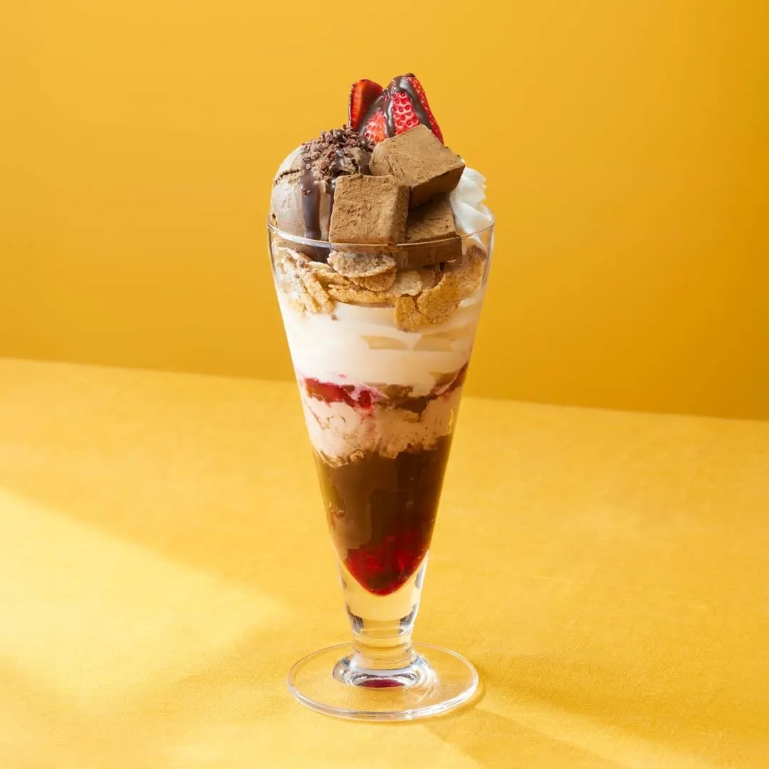 グラスに盛り付けられたパフェ。チョコレートアイス、チョコレート、フレーク、いちご、クリームなどが層状に重なっている。