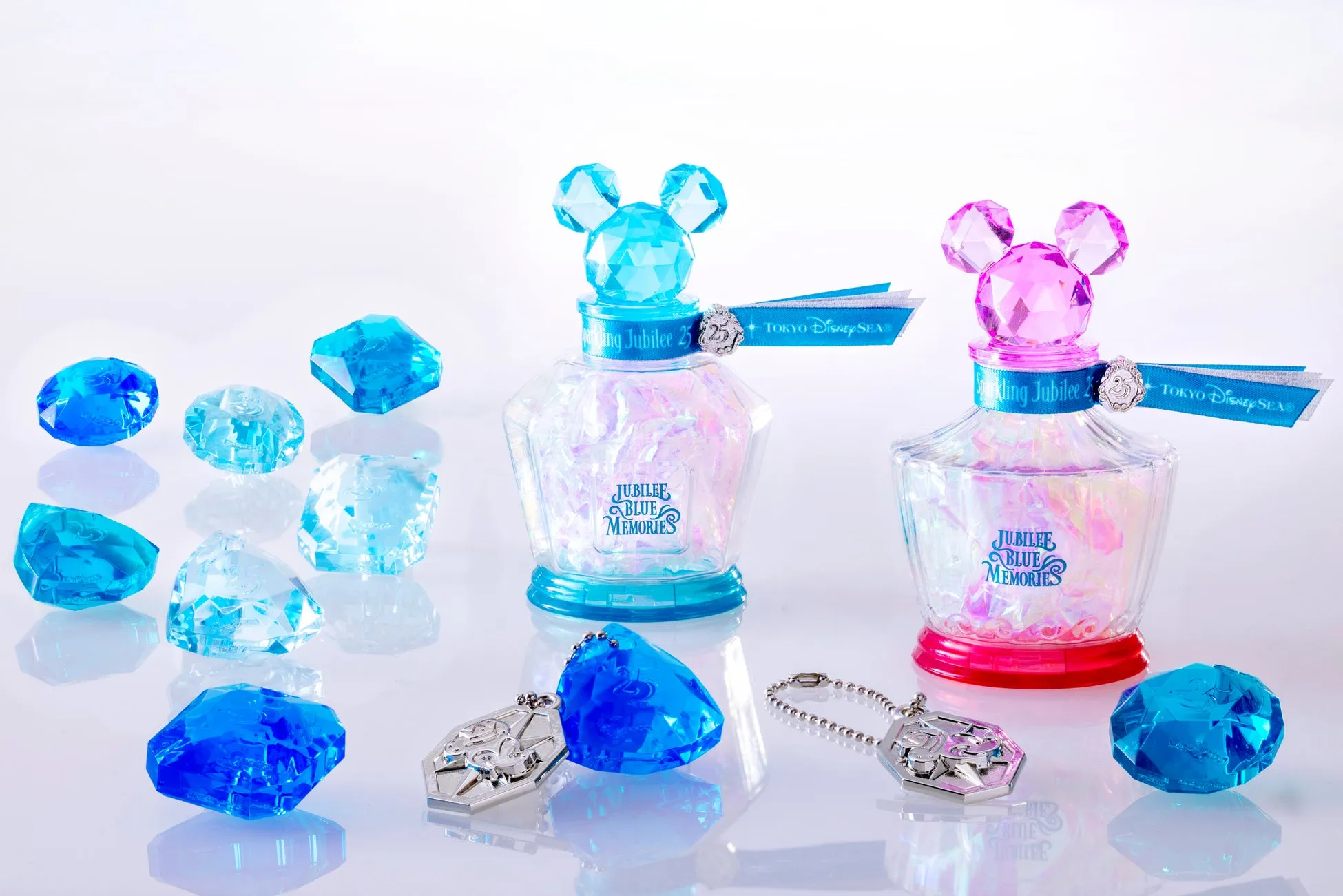 ディズニーシー25周年記念の香水瓶と宝石のようなアクセサリーのセット。ブルーとピンクの香水瓶はミッキーのシルエットをしており、宝石が散りばめられています。