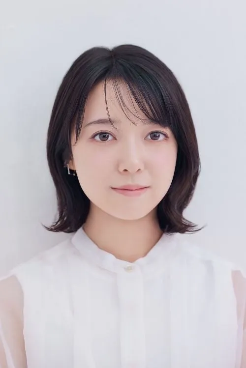 白いシャツを着た女性のポートレート。彼女は短い黒髪で、正面を見つめている。