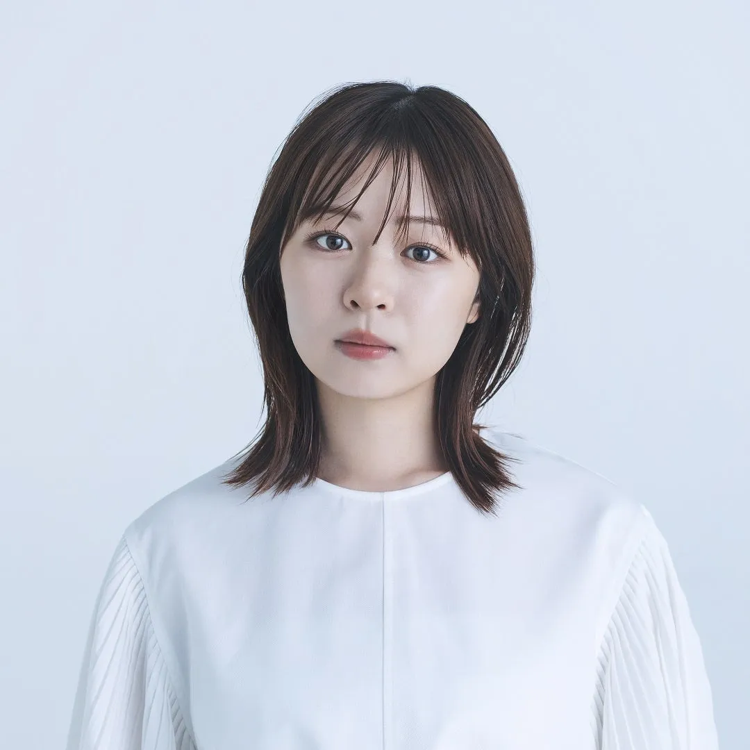 白い背景に、白いシャツを着た女性のポートレート。