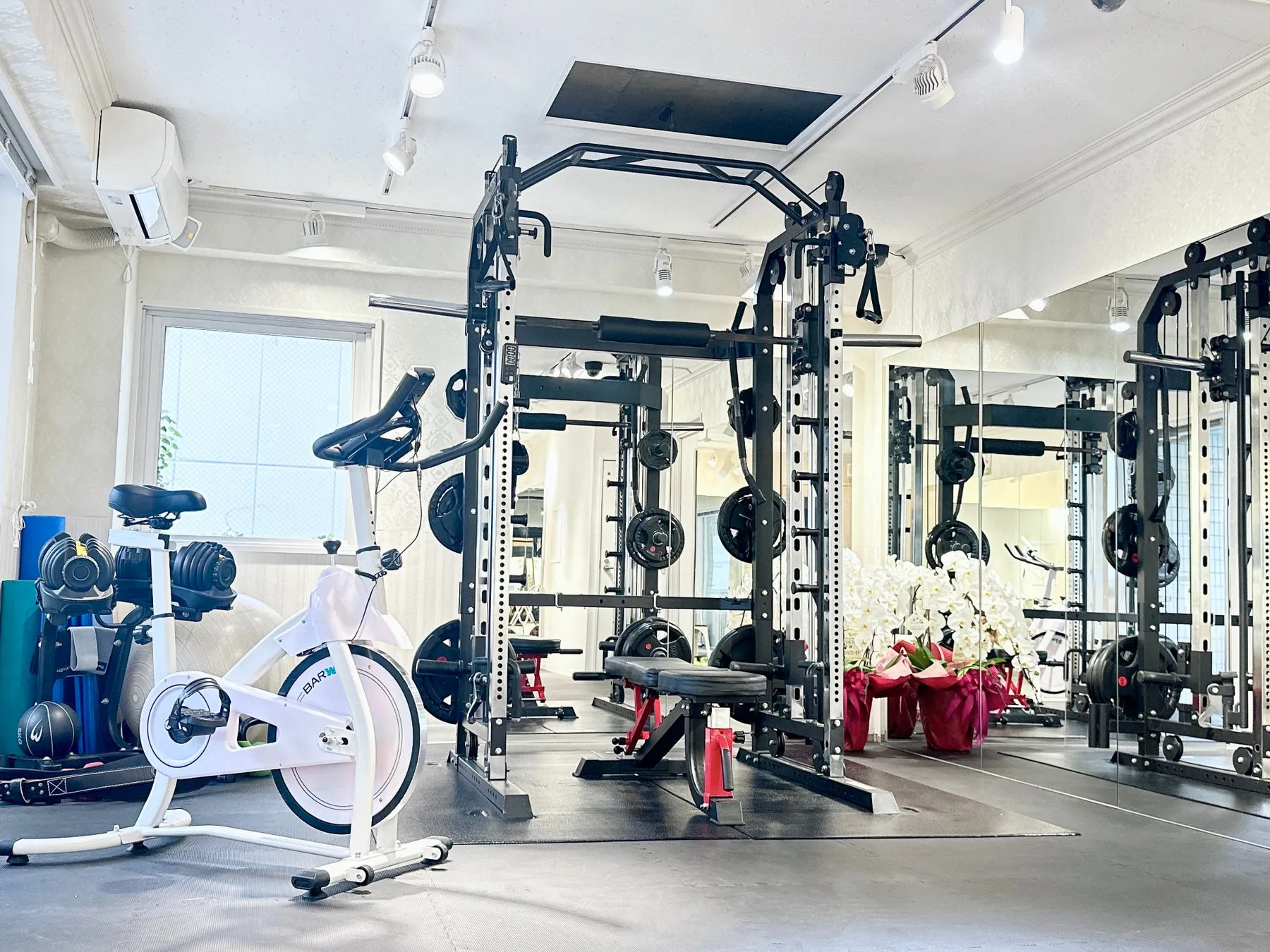 ジムの内観写真。トレーニング器具やエアロバイク、鏡などが写っています。