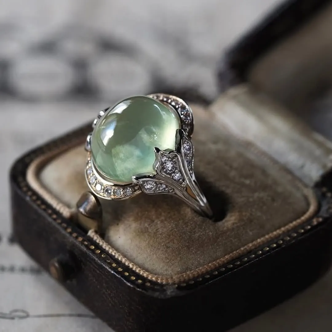 ジュエリーケースに入った、緑色の宝石とダイヤモンドがあしらわれた美しい指輪