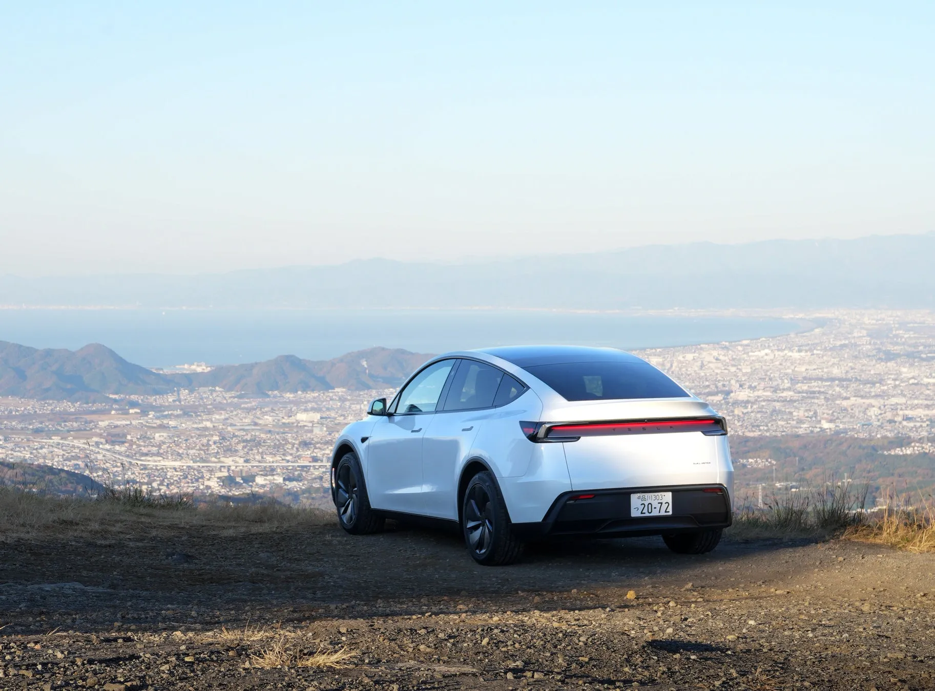 山の上から撮影された白いテスラ車