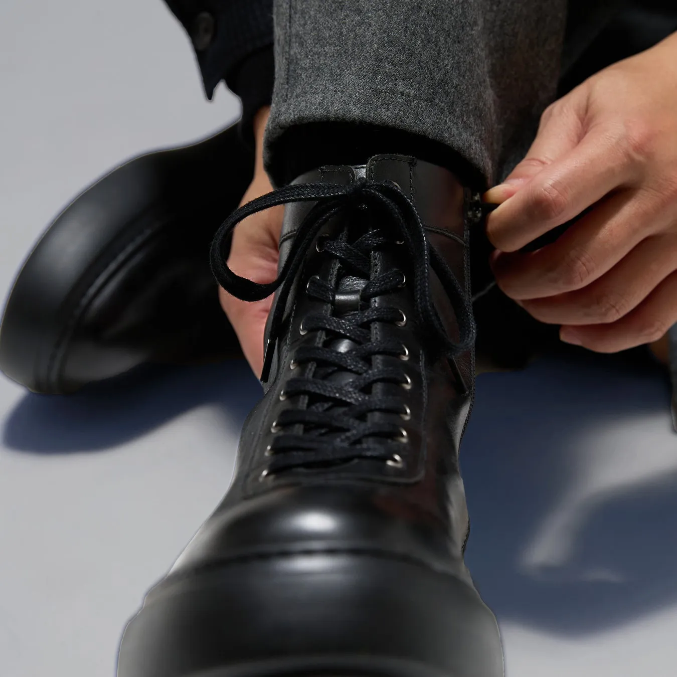 ブーツの靴紐を結んでいる男性の手元