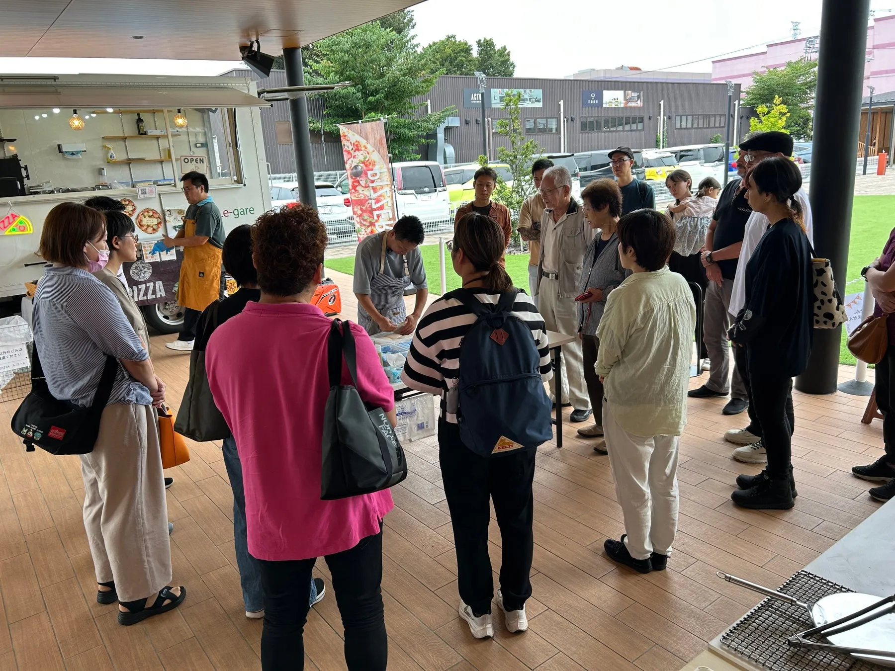 ピザ屋台の前でピザ作りの様子を見学する人々の様子。