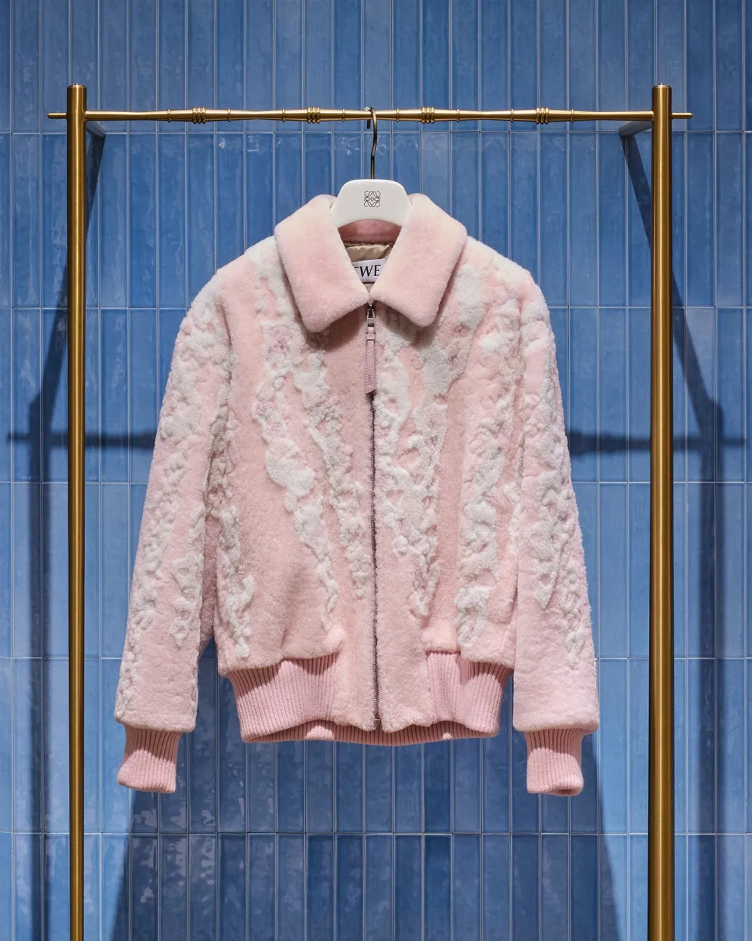 ピンク色のジャケットがハンガーラックにかけられている写真。