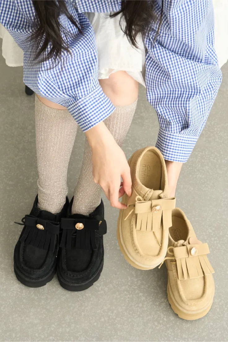 女性が、黒とベージュの靴を両手に持って持っている写真