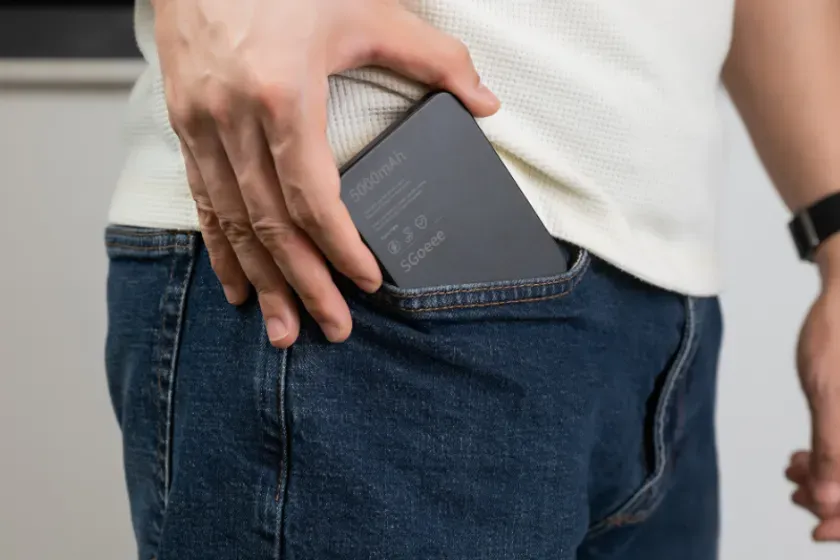 ジーンズのポケットにスマホが入っている様子を写した写真です。手でポケットにスマホを入れている様子です。