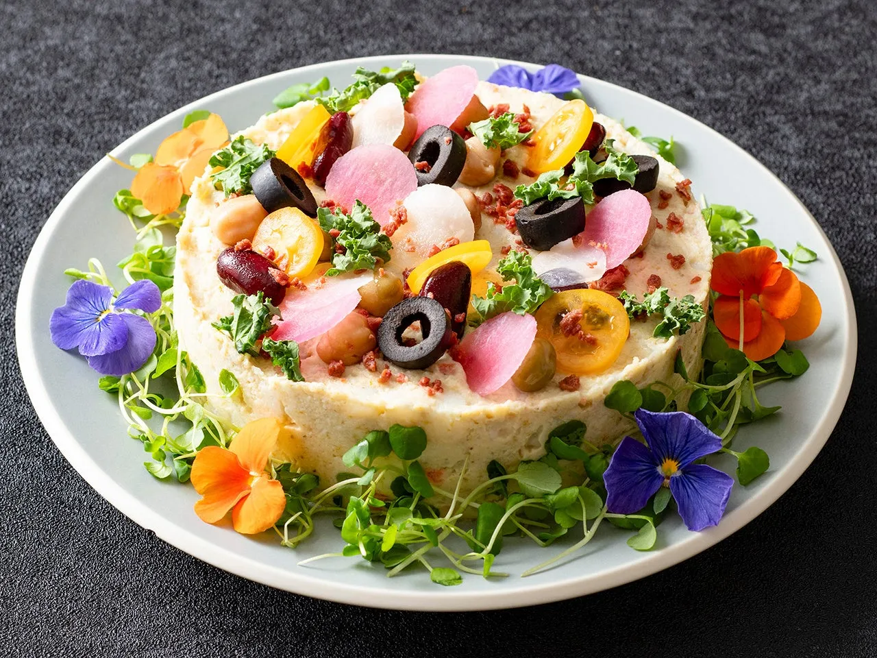 円形に盛り付けられた料理。様々な野菜や花で飾り付けられており、彩り豊か。