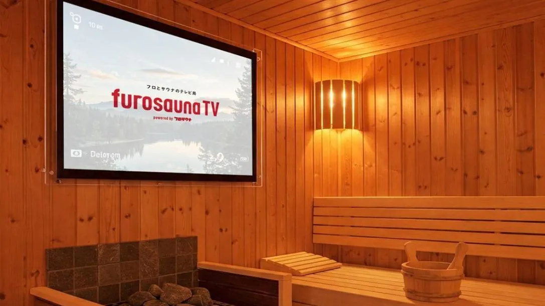 サウナ室の様子。壁にはテレビが設置され、テレビには「furosaunaTV」のロゴが表示されている。サウナベンチやバケツなども見える。