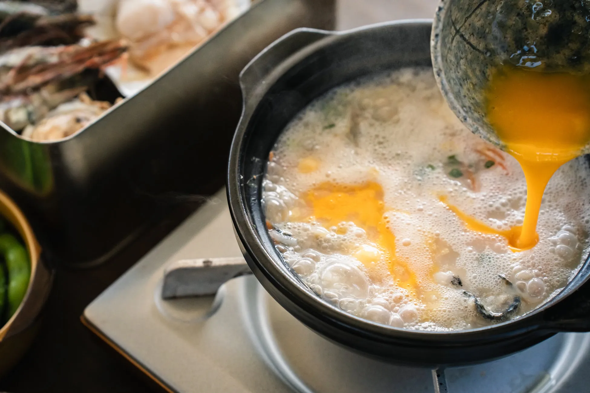 卵を落としている鍋のクローズアップ写真。他の食材も見える。
