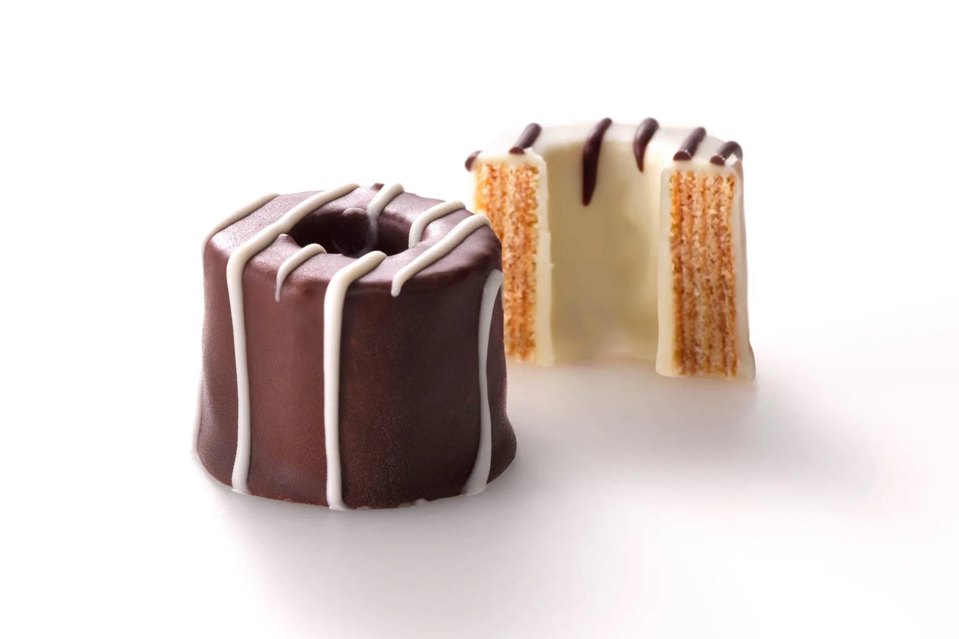 チョコレートでコーティングされた2つのバウムクーヘン。1つはダークチョコレートで、白い線が引かれており、もう1つは白いチョコレートで、チョコレートの線が引かれています。