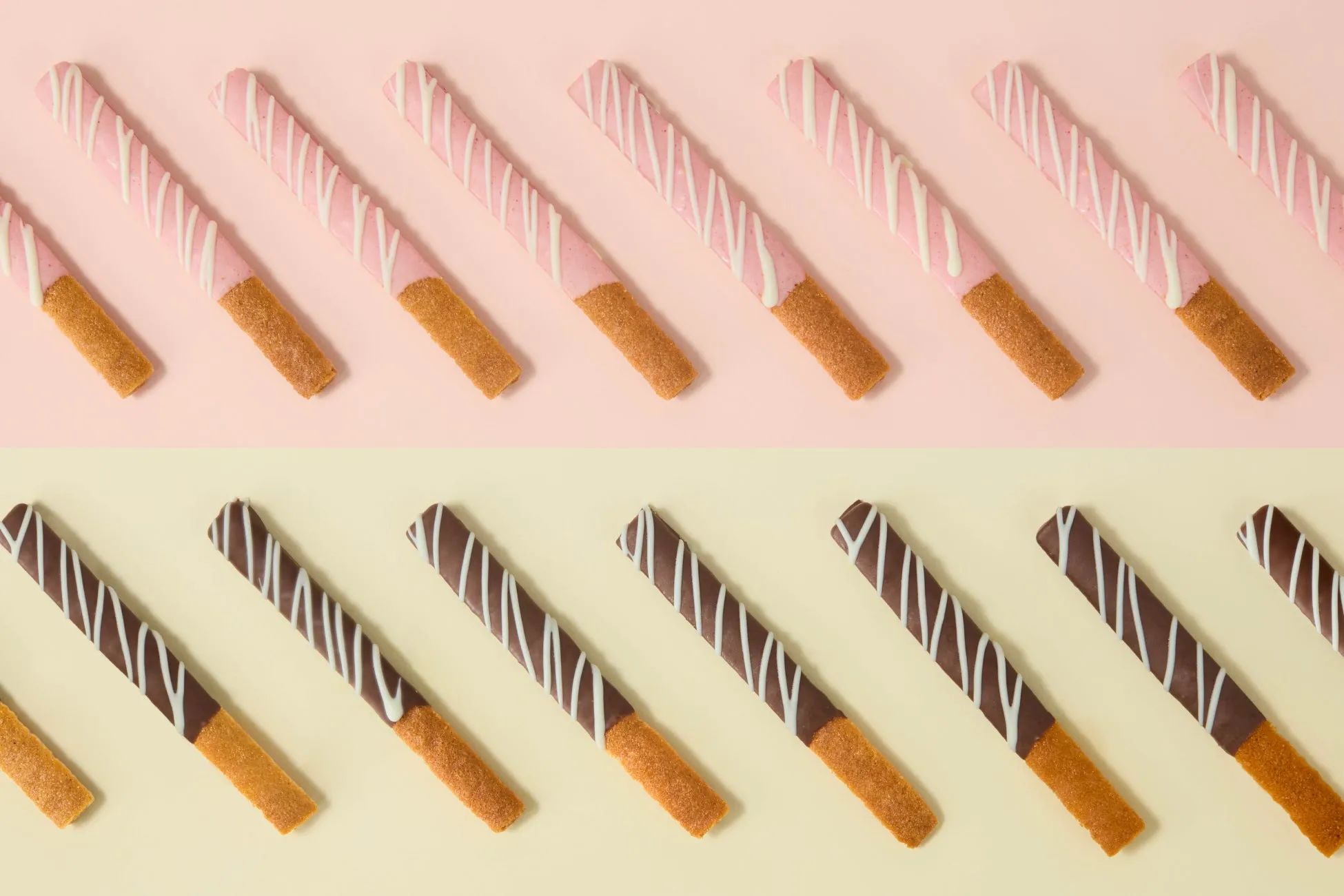 ピンクとチョコレートでコーティングされたお菓子のスティックが、ピンクと黄色の背景に並べられた写真です。