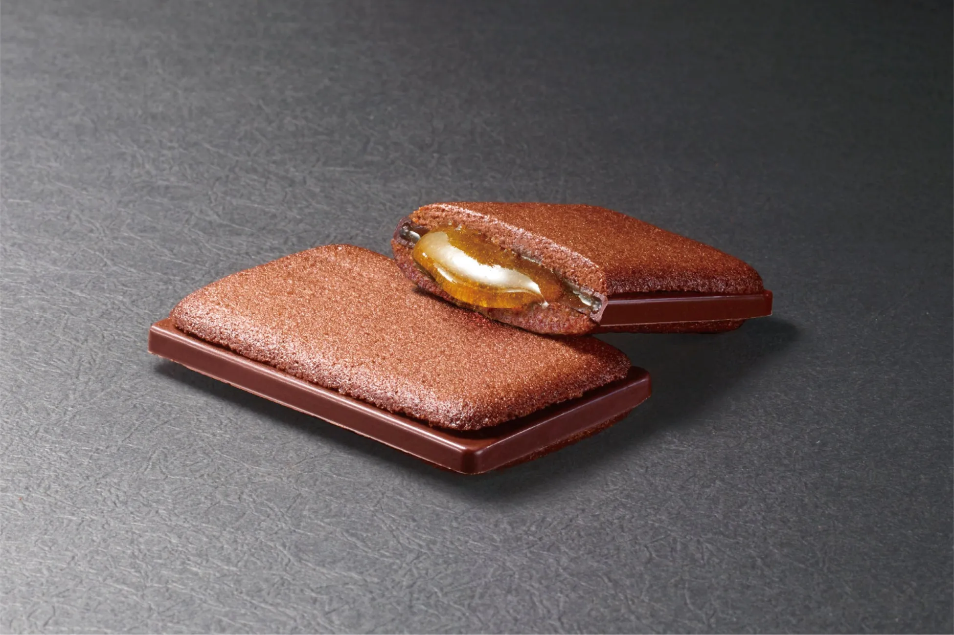 チョコレート菓子が2つ置かれた写真です。チョコレートのクッキー生地で、中にキャラメルソースのようなものが入っています。