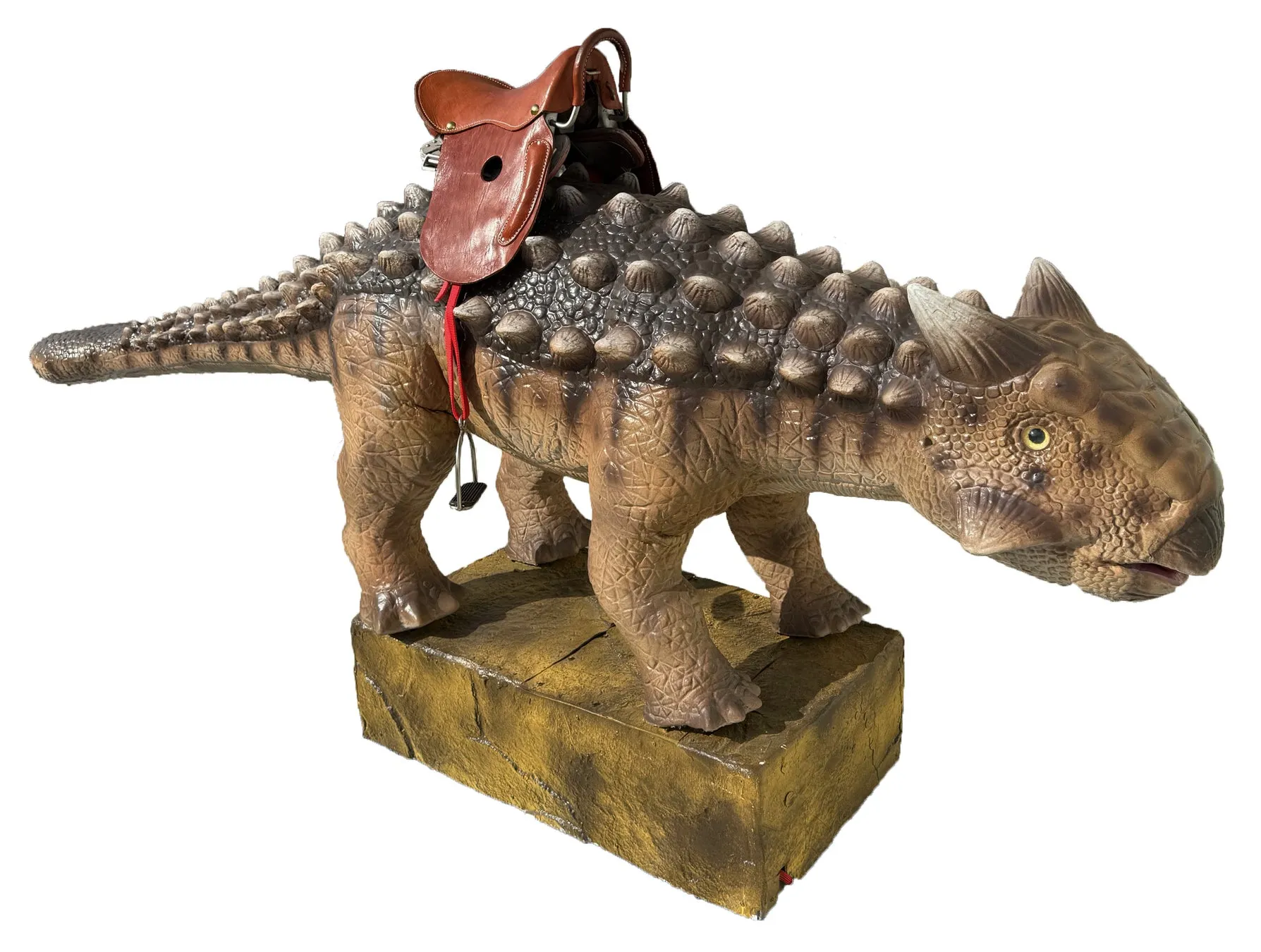 茶色い装飾が施されたアンキロサウルスの像。像には革の鞍が取り付けられています。像は、茶色い長方形の台座の上に立っています。