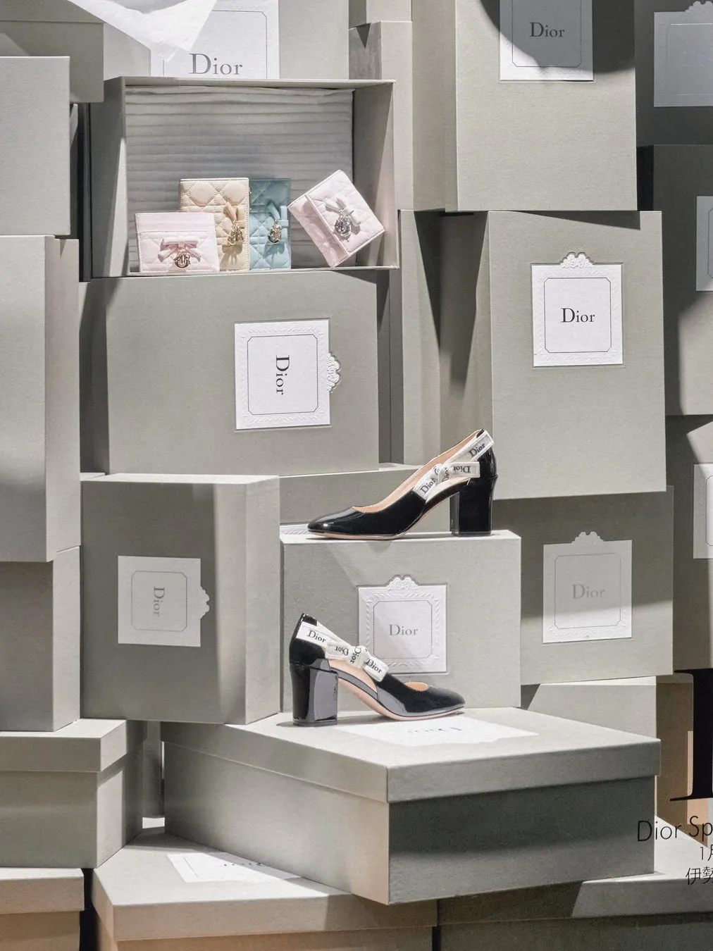 Diorの展示ディスプレイ。グレーの箱の中に靴や財布が配置され、Diorのロゴが施されている。