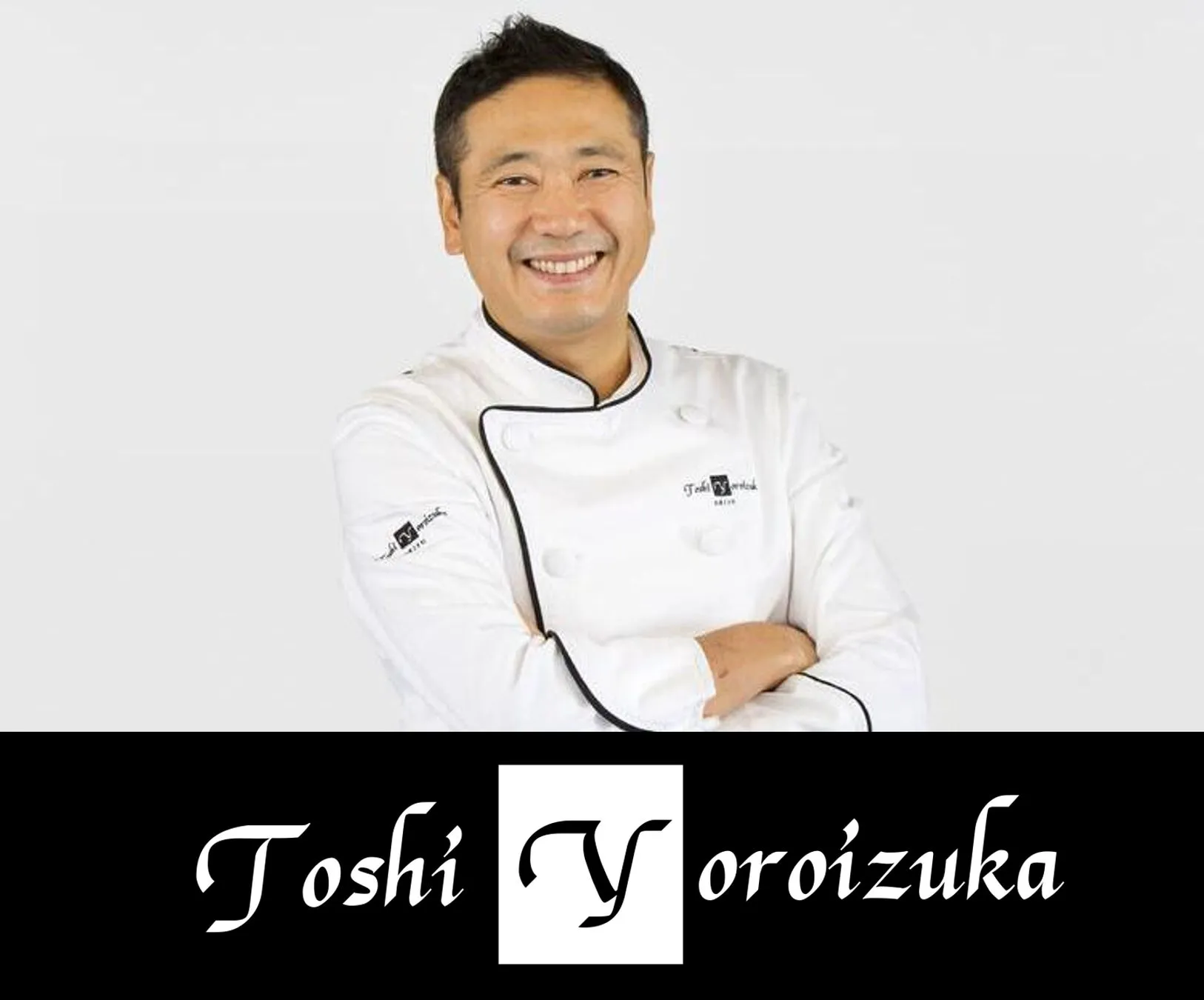 白いコックコートを着た男性のポートレート。彼は笑顔で、腕を組んでいる。彼の名前「Toshi Yoroizuka」は画像の底部に表示されている。