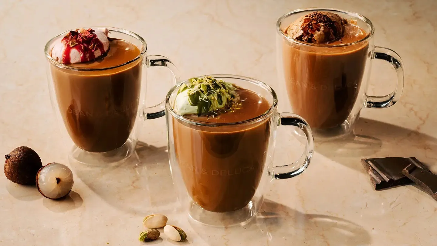 3杯のチョコレートドリンク。トッピングは、緑色のピスタチオ、ピンク色のクリーム、チョコレートフレーク。