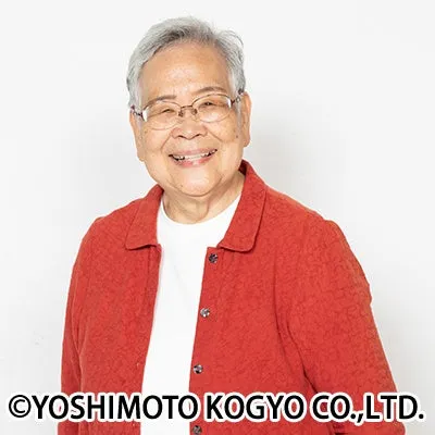 笑顔の高齢女性のポートレート。彼女は眼鏡をかけ、赤いジャケットを着ている。