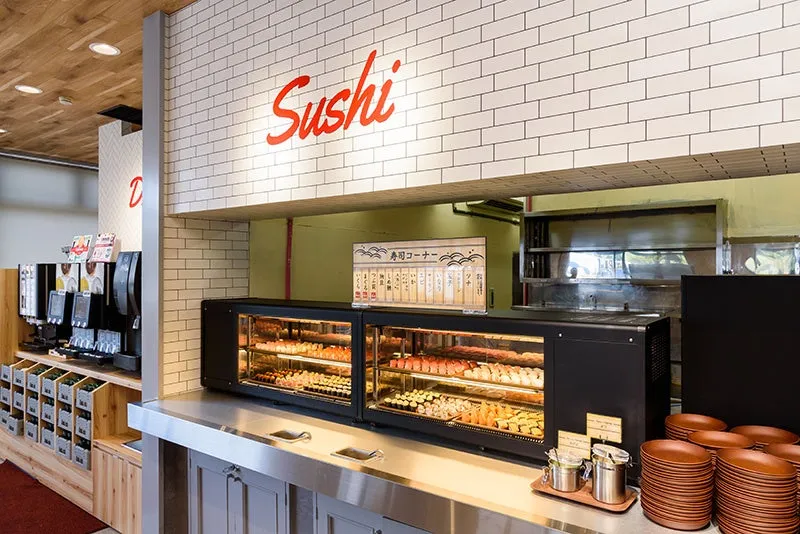 寿司を提供する店の内部の様子。寿司が陳列されたショーケース、調味料、皿などが写っています。