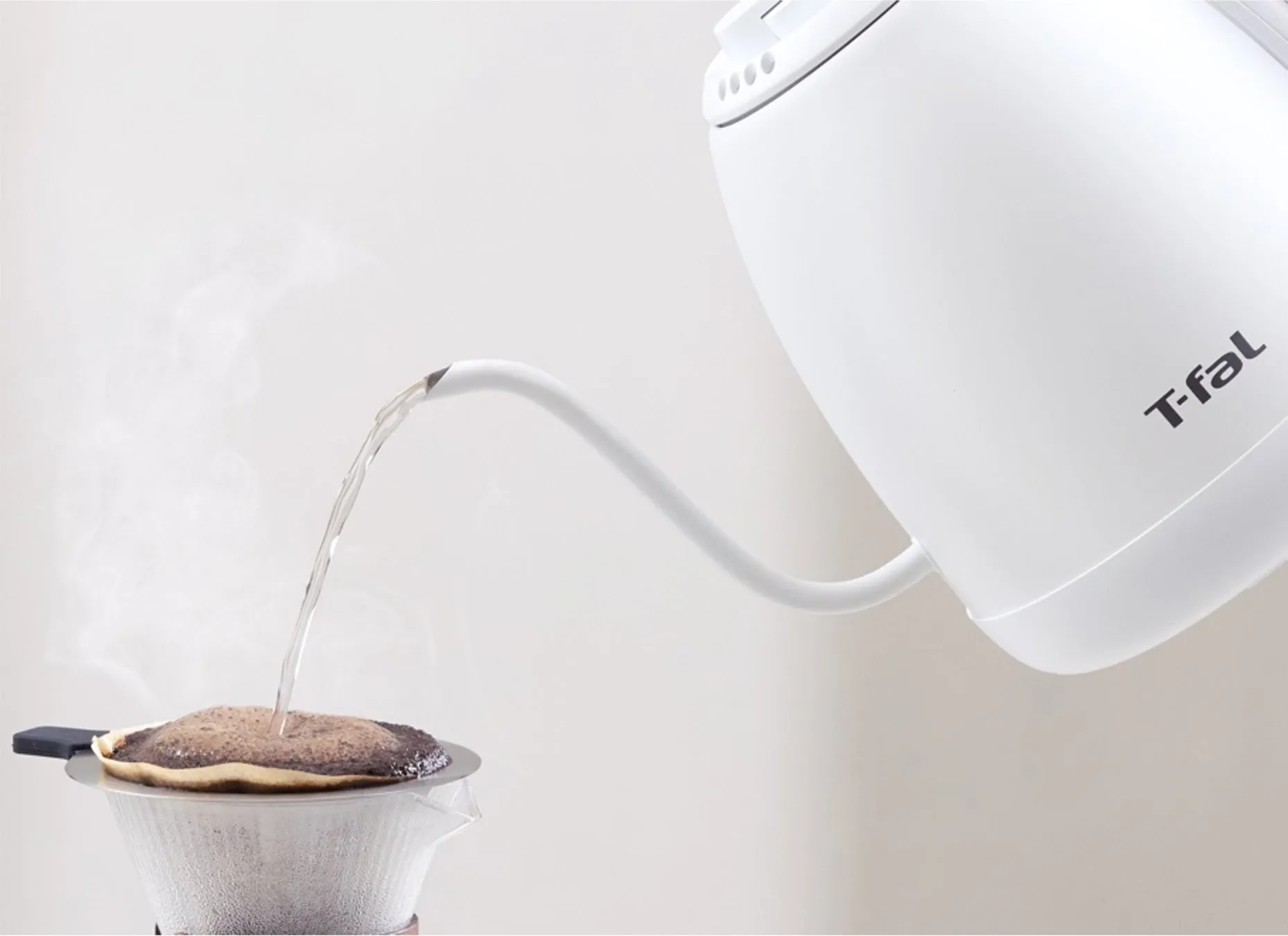 お湯を注いでコーヒーをドリップしている様子を写した写真。白い電気ケトルから細くお湯が注がれ、コーヒーフィルターにセットされたコーヒー粉に落ちている。湯気も立っている。