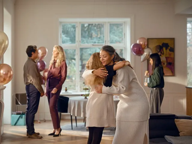 人々が抱き合ったり、会話したり、お祝いをしている様子を描いた室内写真