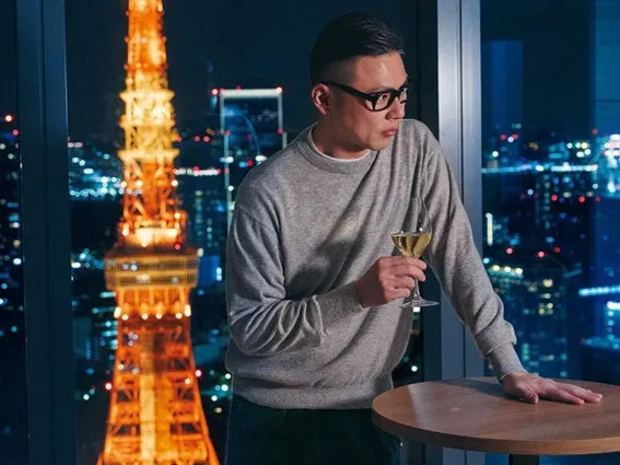 東京タワーを背景に、窓際でワイングラスを持つ男性