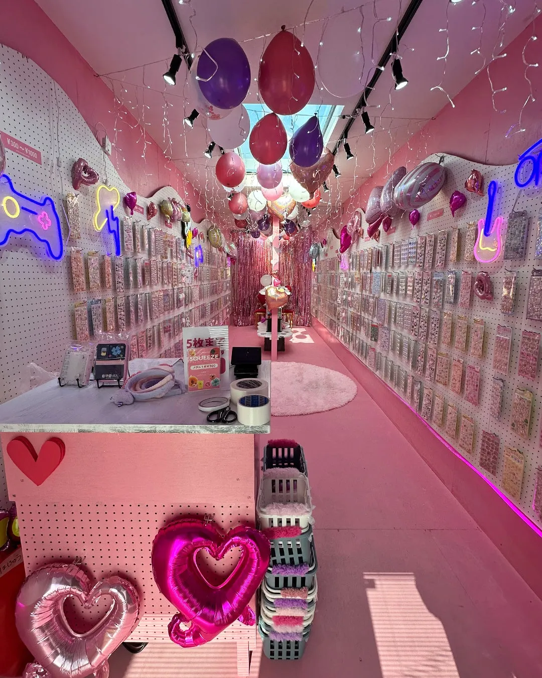 ピンクを基調とした内装の店内で、風船や商品が陳列されている様子を捉えた写真です。