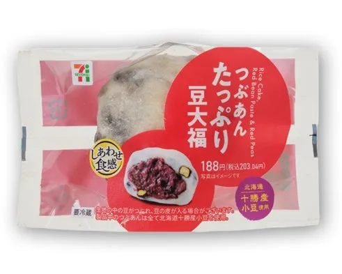 7-Elevenの豆大福のパッケージ。赤色の丸いラベルに商品名、価格、説明が記載されている。大福の断面図も描かれており、中身の餡が見える。