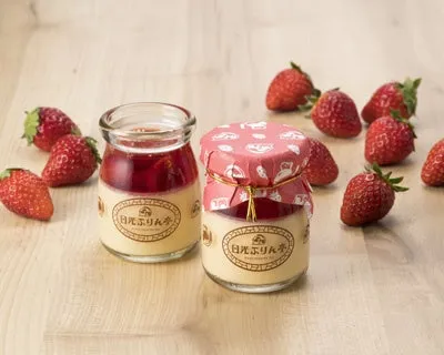 2つのプリンとイチゴが木製のテーブルの上に置かれている写真