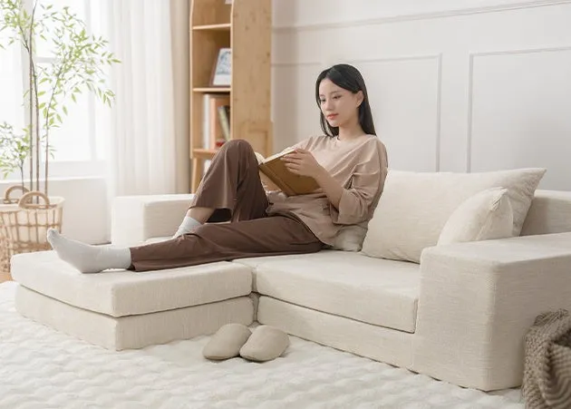 女性がソファーに座って本を読んでいる様子。