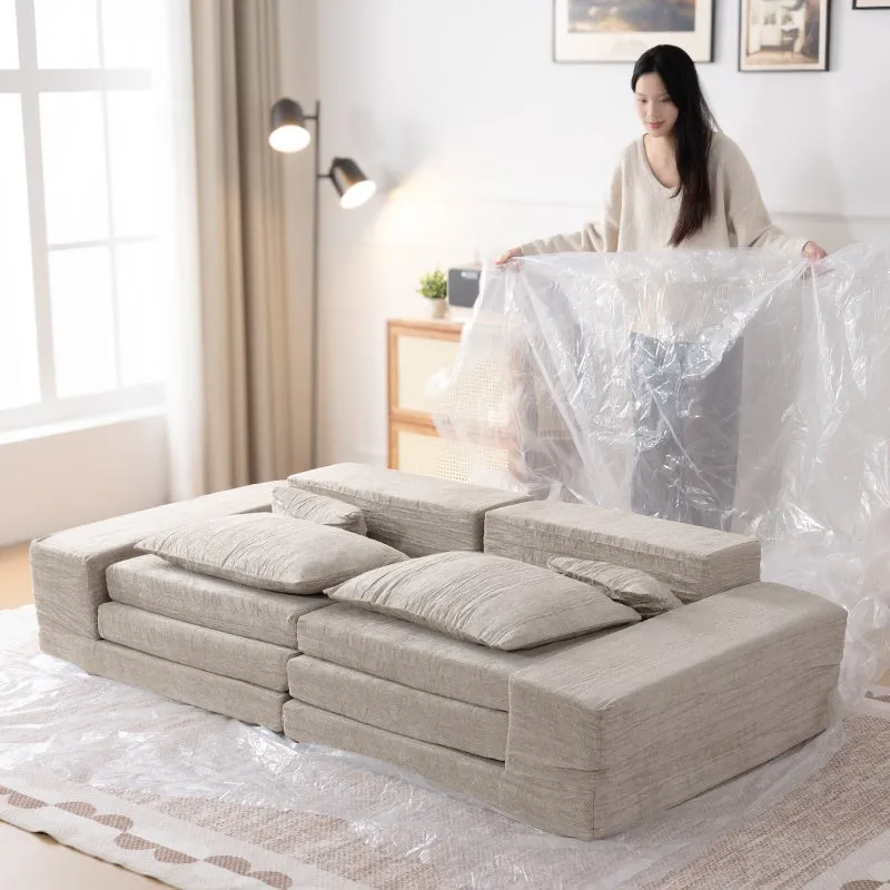 女性が、新しいソファを保護用のビニールシートから出している様子。