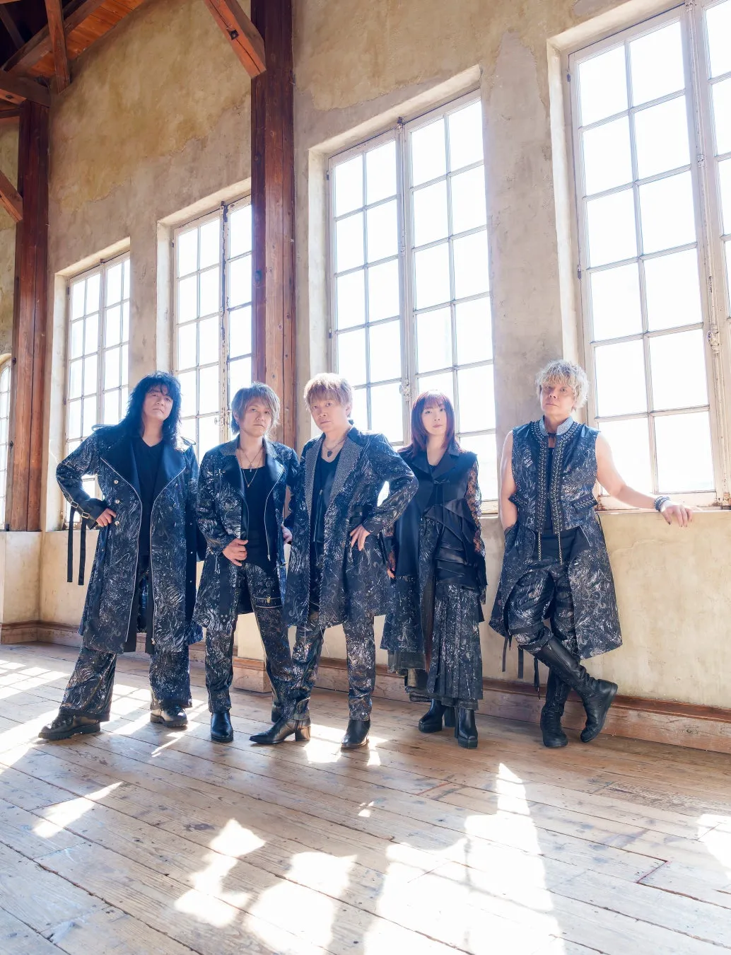 5人のアーティストが、窓の前に立ってポーズをとっている写真