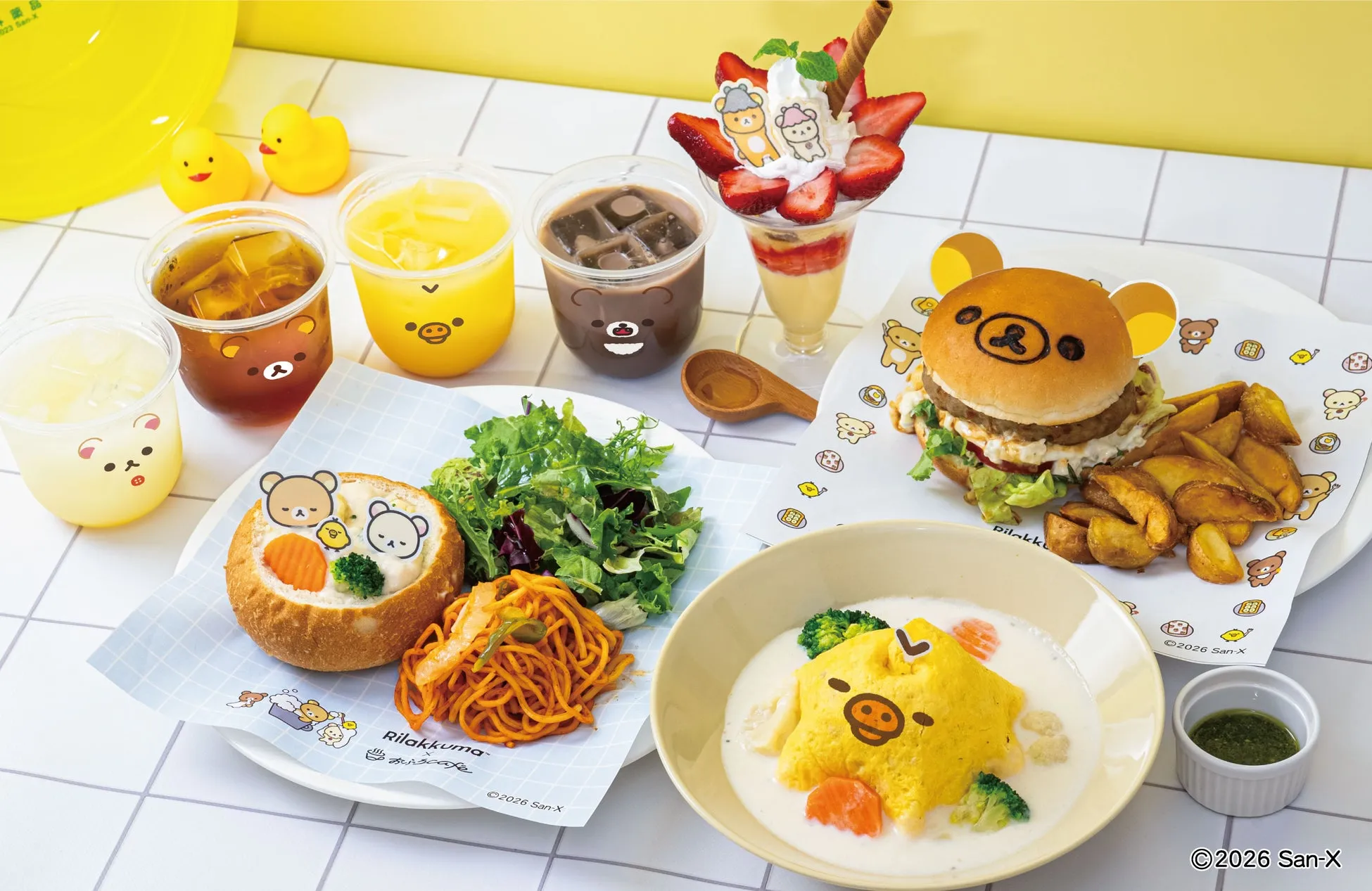 Rilakkumaをモチーフにした様々な料理が並んだ写真。ハンバーガー、オムライス、パフェ、ドリンクなど、可愛らしいキャラクターの装飾が施されている。