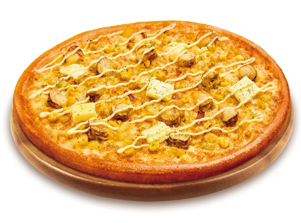 丸いピザで、トッピングにはコーン、貝類、バター、マヨネーズが乗っています。木製の台座に載せられています。