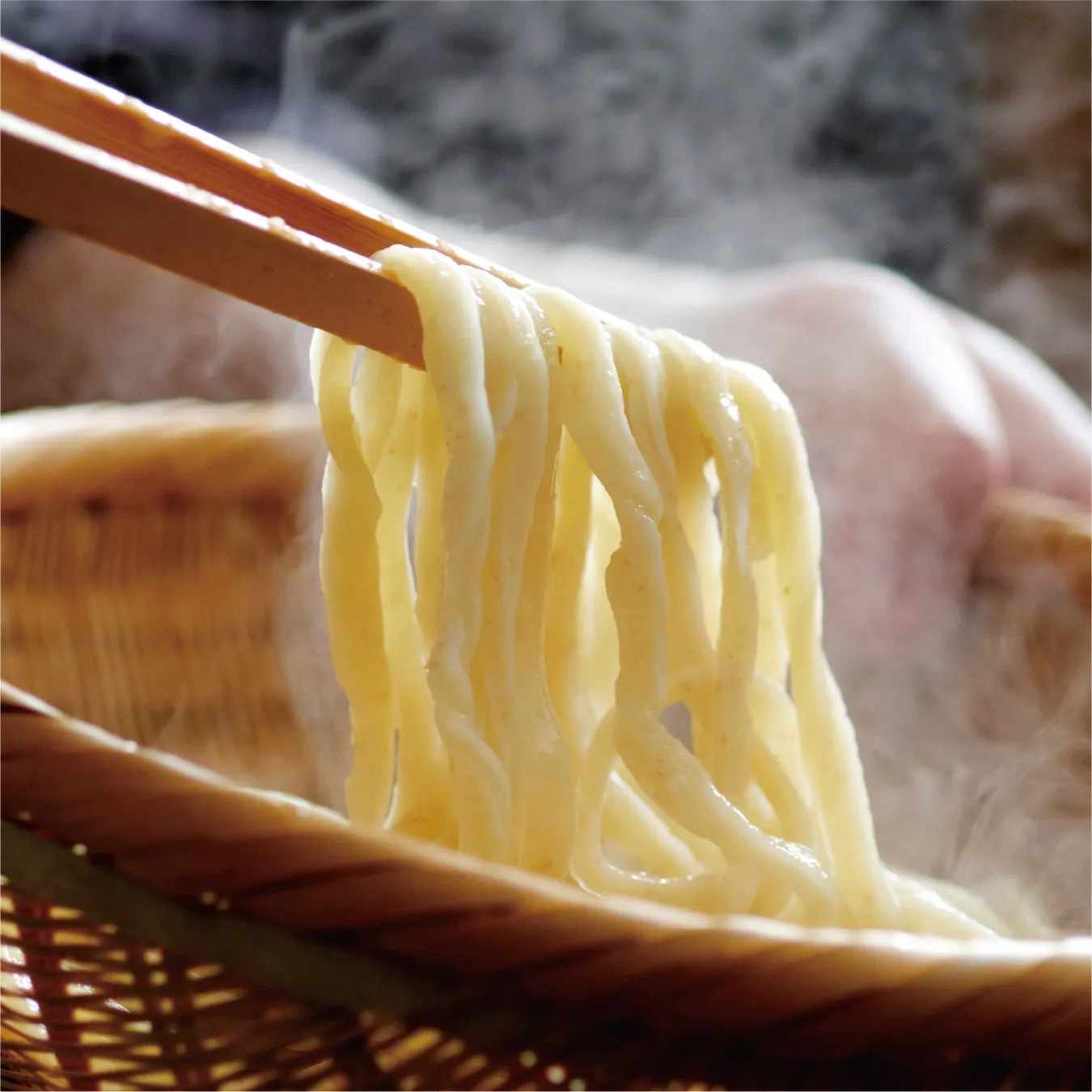 箸で持ち上げられた湯気の立つ麺のクローズアップ。