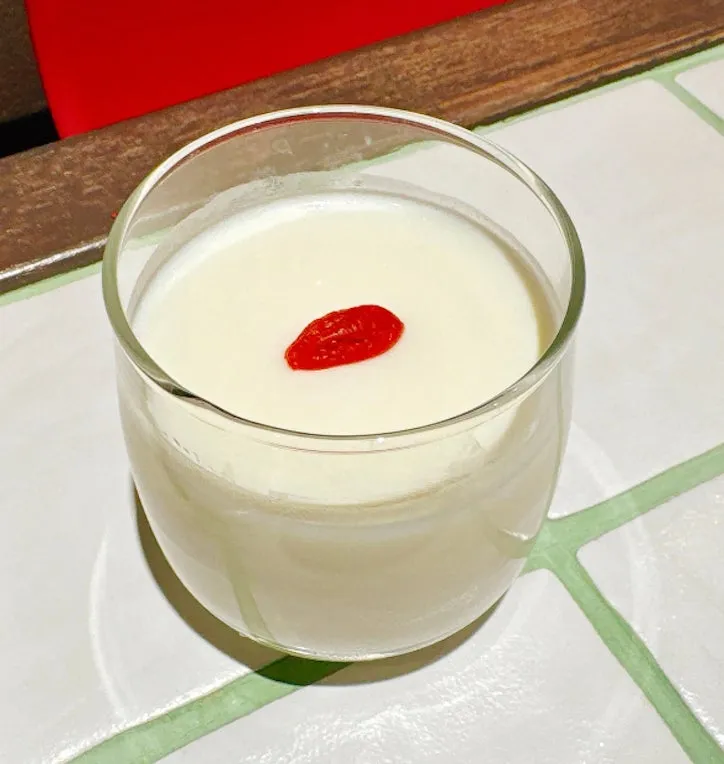 白い飲み物に赤い実が乗った画像。