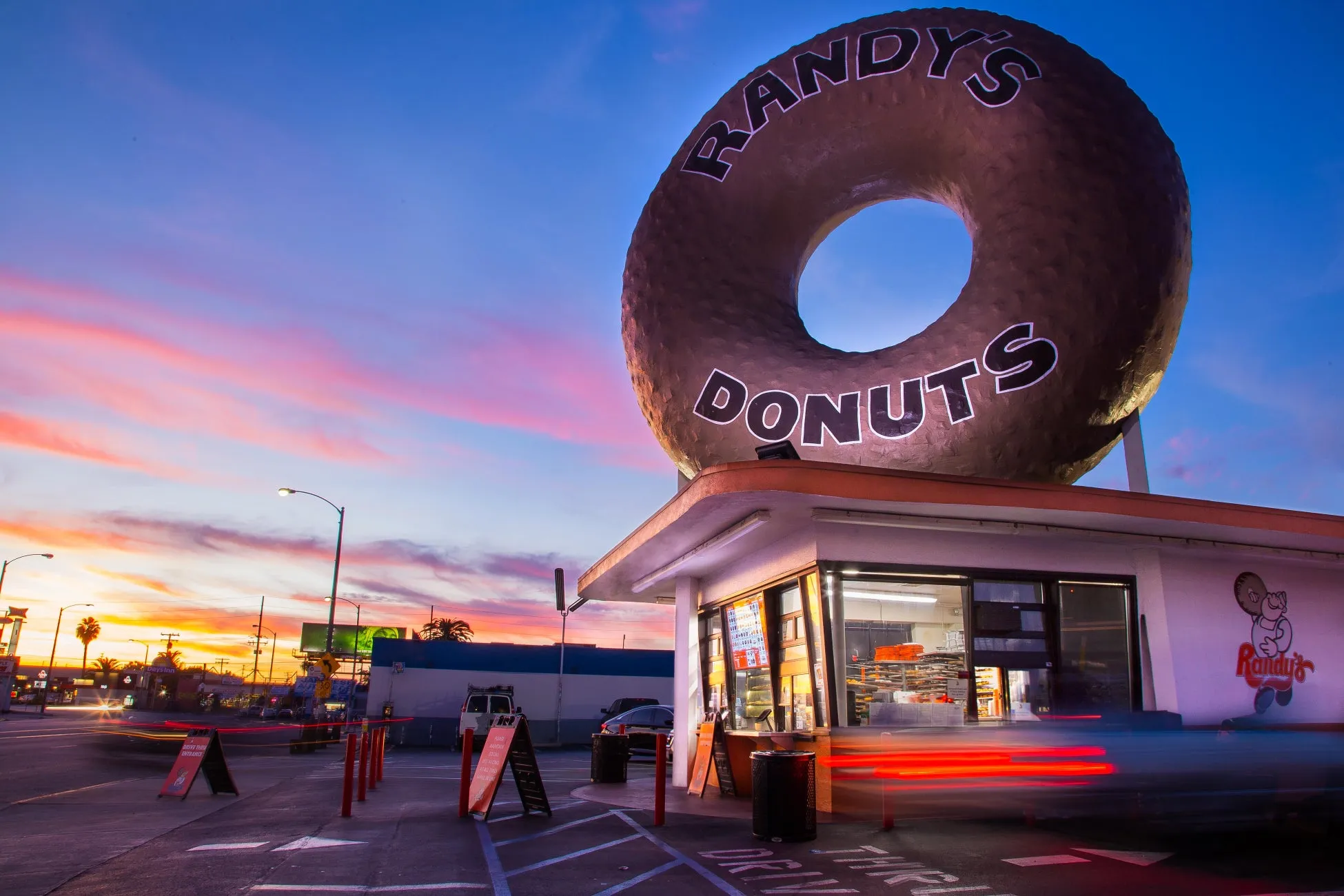 巨大なドーナツの看板が特徴的なRandy's Donutsの夕焼け時の写真です。