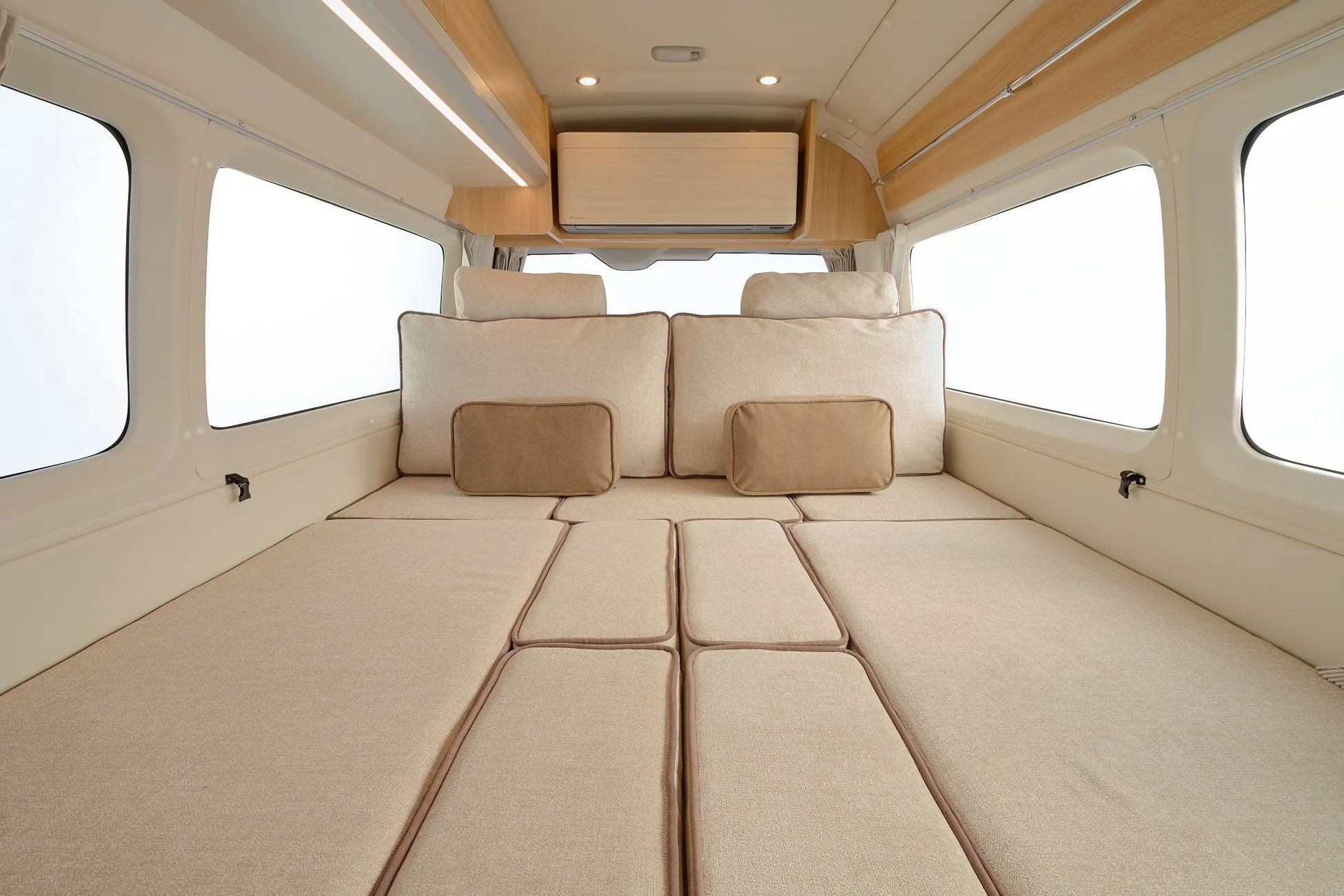 キャンピングカーの内部の様子。ベッド、クッション、窓が写っています。