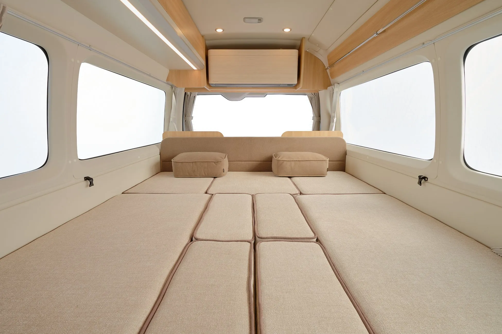 キャンピングカーの内部の様子。ベッドが配置され、窓から光が入る。