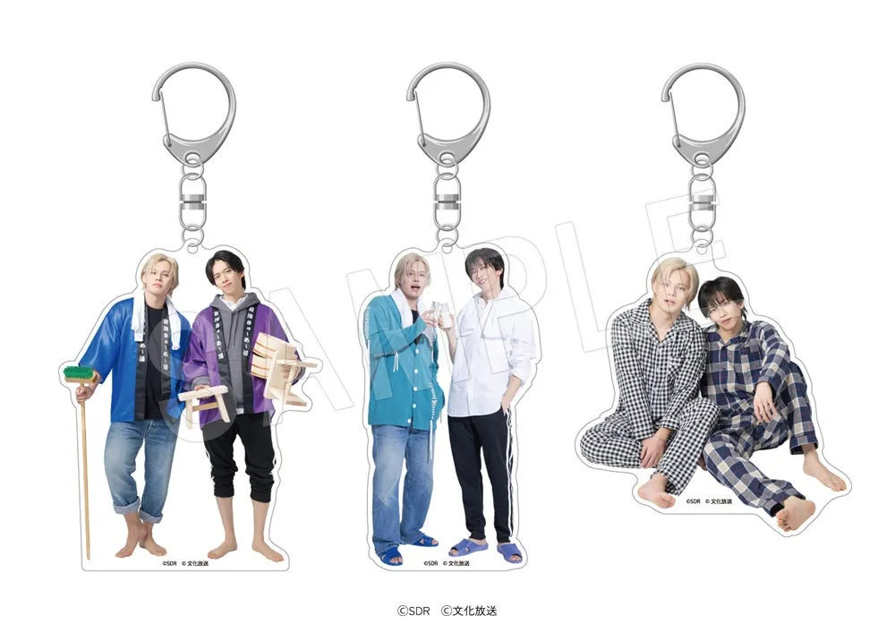 3つのアクリルキーホルダー。それぞれ2人組の男性が描かれており、左のキーホルダーは、青い法被を着て箒を持つ男性と、紫の法被を着て木製の椅子を持つ男性が描かれています。真ん中のキーホルダーは、青いカーディガンを着てグラスを持つ男性と、白いシャツを着た男性が描かれています。右のキーホルダーは、チェック柄のパジャマを着た男性2人が描かれています。